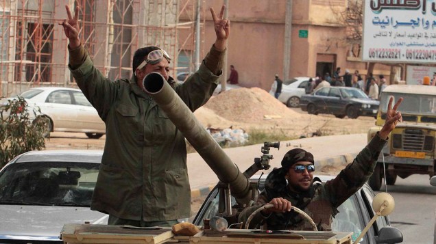 Rebeldes comemoram após ataque aéreo, que destruiu tanques das forças de Muamar Kadafi, em Bengasi