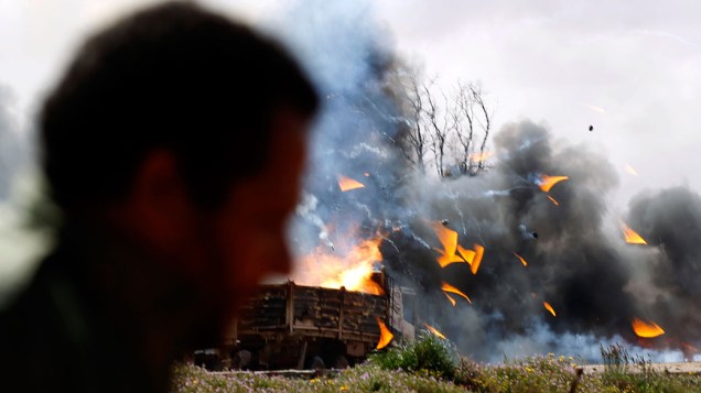 Rebeldes observam destroços de caminhões atingidos por ataque aéreo