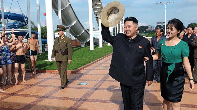O líder norte-coreano, Kim Jong-Un, visita parque de diversões recém-inaugurado em Pyongyang, na Coreia do Norte, escoltado por soldado e acompanhado da mulher, Ri Sol-Ju