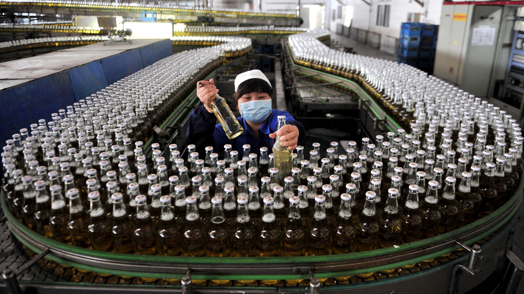 Funcionária trabalha na linha de produção de uma cervejaria em Shenyang, província de Liaoning, China