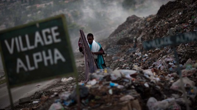 Em Porto Príncipe, homem recolhe roupas no lixão