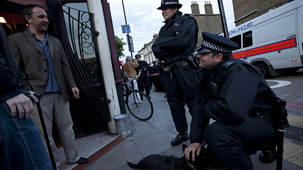 Policial brinca com cachorro e conversa com cliente de um bar no bairro de Hackney na tarde desta quarta-feira: ruas de Londres recuperam tranquilidade após distúrbios