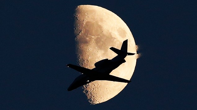 Avião se prepara para pousar no aeroporto Internacional de Viena-Schwechat, na Áustria enquanto lua é vista ao fundo