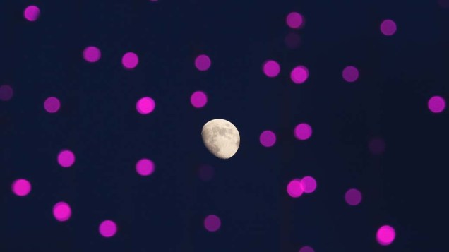 A lua vista através de vidro com luzes refletidas em parque em Hong Kong, China