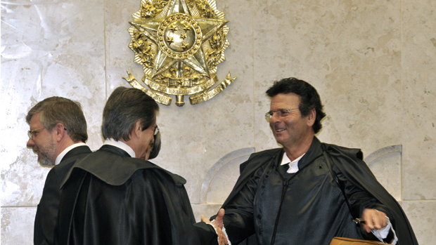 O novo ministro do STF, Luiz Fux, cumprimenta Cezar Peluso, presidente do tribunal. Ao fundo, o presidente da Câmara dos Deputados, Marco Maia