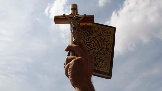 Egípcio carrega a cruz cristã com o Corão, durante manifestação a favor da tolerância religiosa, no centro do Cairo