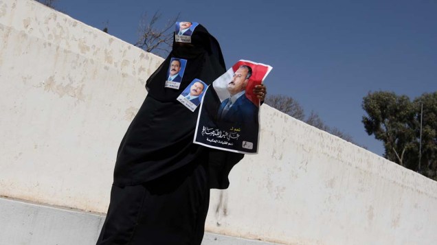 Manifestante pró-governo com imagens do presidente Ali Abdullah Saleh durante manifestação no centro de Sanaa, Iêmen