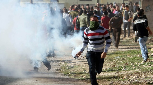 Manifestante atira lata de gás lacrimogênio em soldados israelenses durante protesto contra a expropriação de palestinos da vila de Kfar Kadum, Cisjordânia