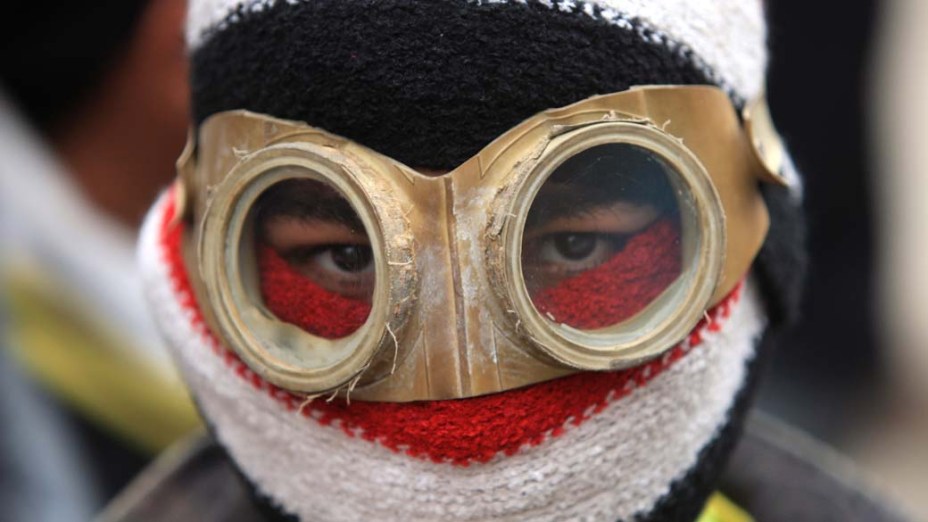 Manifestante mascarado durante confrontos com a polícia no Cairo, Egito