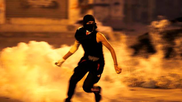 Em Manana, capital do Barein, manifestante corre segurando lata gás lacrimogêneo disparado por policiais durante confrontos após a procissão para visitar o túmulo de Abdulsamad, morto há duas semanas por um tiro disparado de um carro em movimento