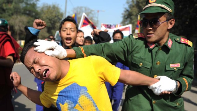 Tibetanos exilados em encenação durante protesto denunciando confrontos entre a polícia chinesa e tibetanos em Nova Délhi, Índia