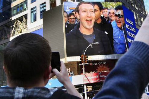 Mark Zuckerberg, fundador do Facebook, aparece em telão em Nova York e pedestres registram momento com tirando fotografias na Times Square