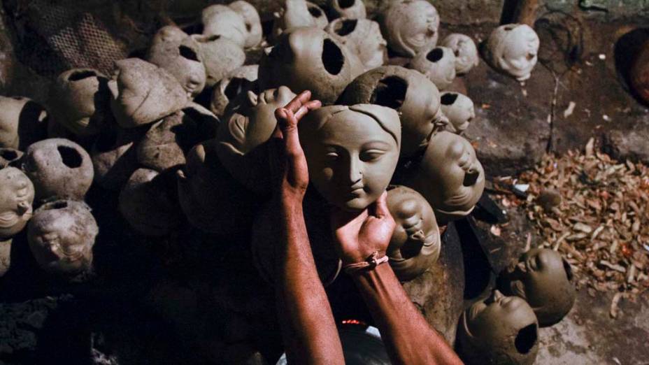 Artesão com máscaras da deusa hindu Durga, durante workshop na cidade indiana de Allahabad