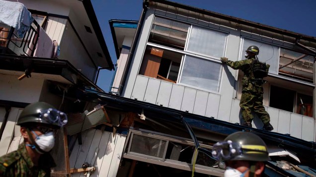 Membros da Força de Autodefesa do Japão procuram vítimas antes de demolir casas danificadas em Miyako, Iwate