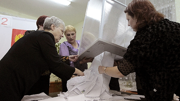 Membros de uma comissão eleitoral local da Rússia esvaziam urna de votação para a contagem dos votos neste domingo