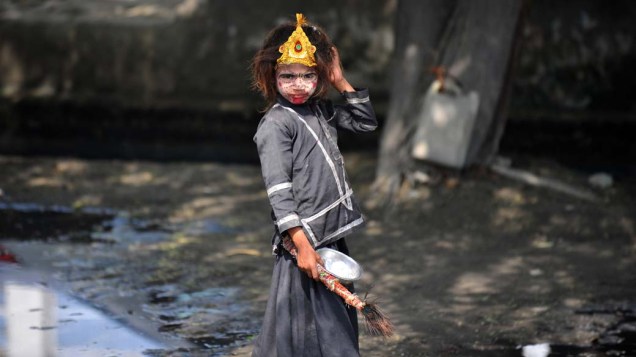 Menina de rua com o rosto pintado em Noida, periferia de Nova Délhi, Índia