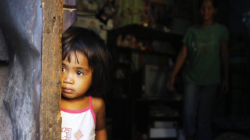 Criança enconstada na porta de um barraco na periferia de Pateros, em Manila, Filipinas