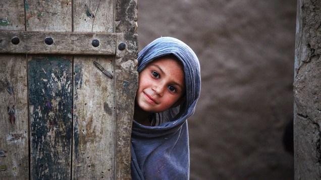 Menina na porta de entrada de sua casa, nos arredores de Peshawar, Paquistão