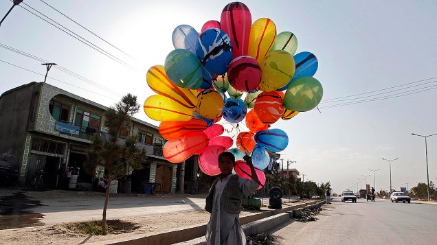 Menino vende balões em uma rua de Cabul, no Afeganistão
