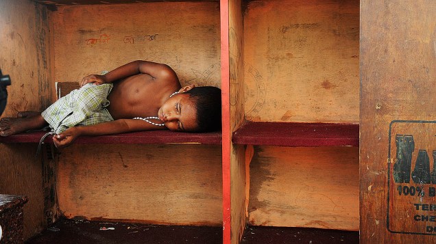 Criança dorme na rua perto de uma barraca para escapar do forte calor que atinge a cidade de Calcutá, na Índia