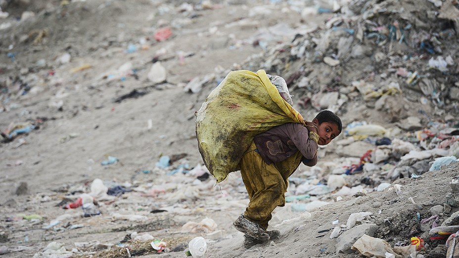 Menino coleta lixo reciclável em aterro, no Afeganistão