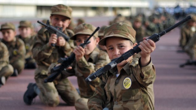 Meninos orfãos apontam seus rifles de brinquedo durante desfile em comemoração ao Dia Nacional do Paquistão em Islamabad