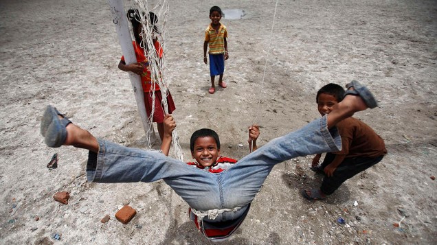 Menino brinca em balanço montado sob um gol em Catmandu, no Nepal