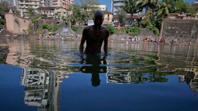 Hinduísta mergulha em lagoa santa no dia de “Mahalaya”, em honra a seus ancestrais, na Índia