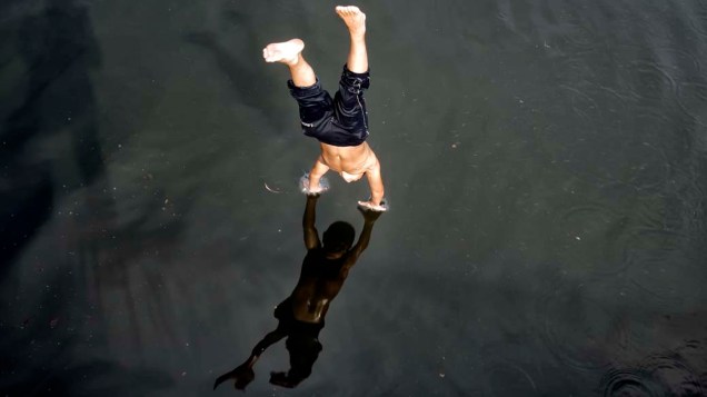 Menino mergulha no rio Dambovita em Bucareste, na Romênia. As temperaturas bateram os 36°C no local, matando cinco pessoas