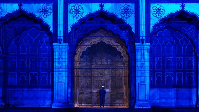 Muçulmano reza dentro da Jama Masjid (Grande Mesquita), iluminada por uma luz azul. A luz faz parte da campanha de prevenção ao diabetes