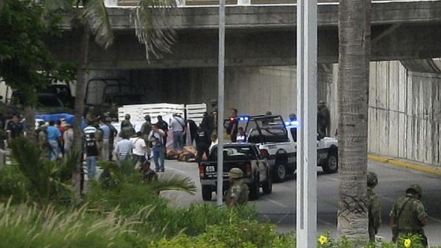 Polícia faz perícia dos corpos encontrados em dois caminhões abandonados embaixo de um viaduto na cidade de Veracruz, uma das mais afetadas pelo embate entre traficantes no país