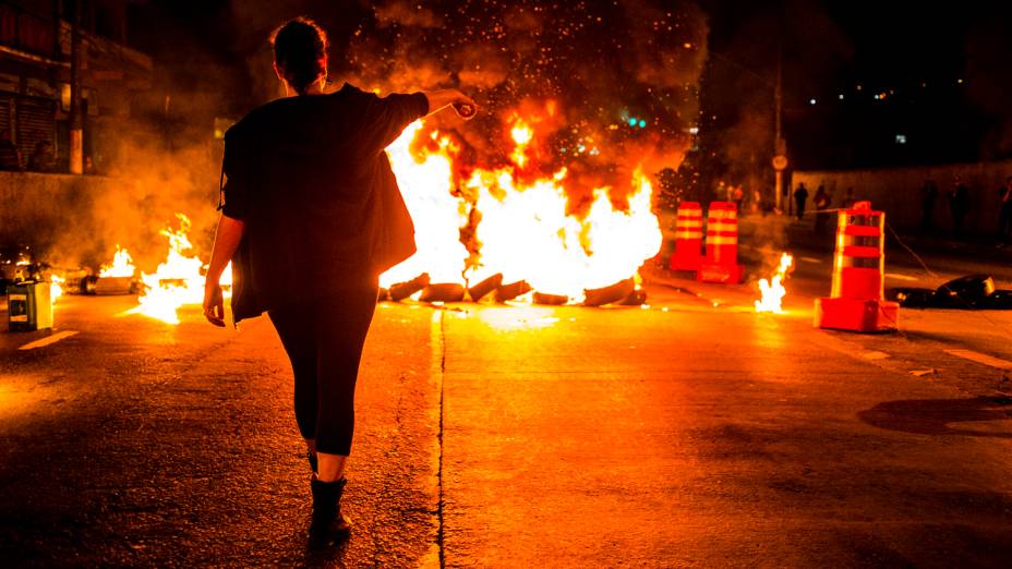 Manifestante interdita a Avenida MBoi Mirim durante protesto organizado pelo Movimento Passe Livre (MPL) contra o corte de linhas e pela duplicação da MBoi Mirim no Largo do Piraporinha, nesta segunda-feira (21), em São Paulo