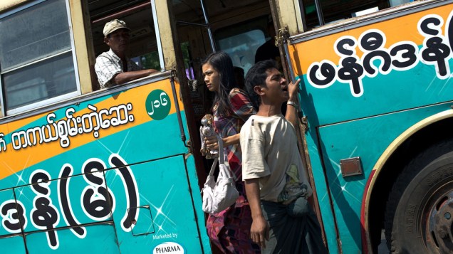 Homem chama passageiros para seu ônibus na periferia de Yangon, a maior cidade de Mianmar