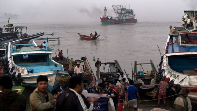 Pescadores e demais trabalhadores aguardam enquanto barco de pesca se aproxima do mercado central de peixes, no porto de Yangon, a maior cidade de Mianmar