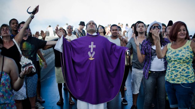 Fieis e turistas se juntam a padre Omar em frente ao Cristo
