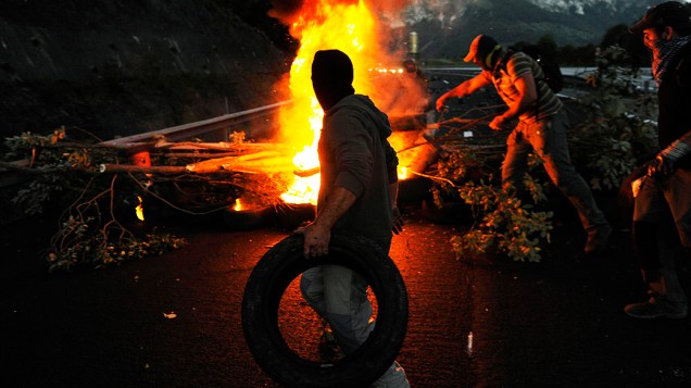 Trabalhador carrega um pneu para montar barricada na autoestrada AP 66, entre Astúrias e Leon, no Norte da Espanha