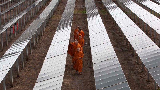 Monges budistas caminham em parque de energia solar na cidade de Ayutthaya, Tailândia