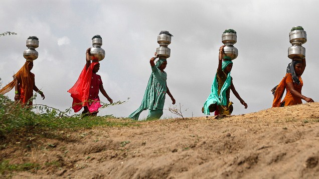 Mulheres carregam potes durante a época de monções em Nani Shinoli, Índia