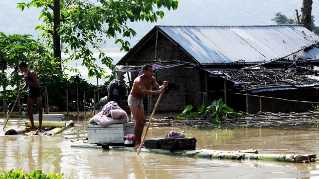 Habitantes transportam os pertences de suas casas alagadas em canoas improvisadas durante a época de monções em Mayong, Índia