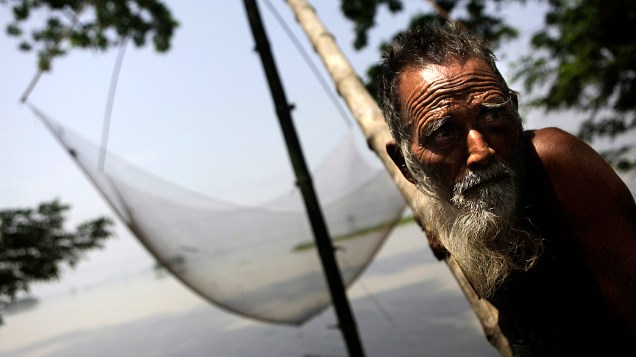 Homem pesca em terras alagadas durante a época de monções em Burhaburhi, Índia