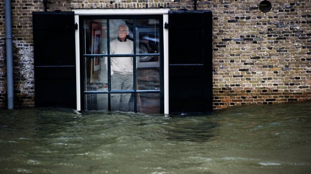 Morador olha o nível da água através de sua janela em Dordrecht, Alemanha