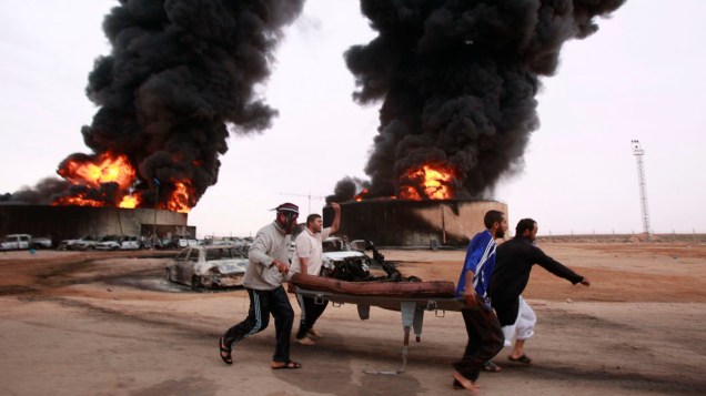 Moradores carregam cadáver encontrado após explosão de petroleiros nos arredores de Sirte, na Líbia