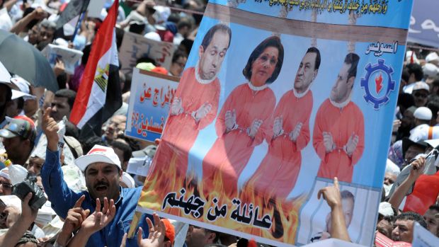 Manifestantes seguram um cartaz com uma montagem, mostrando membros da família do ex-ditador egípcio na forca