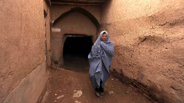 Mulher afegã caminha em viela