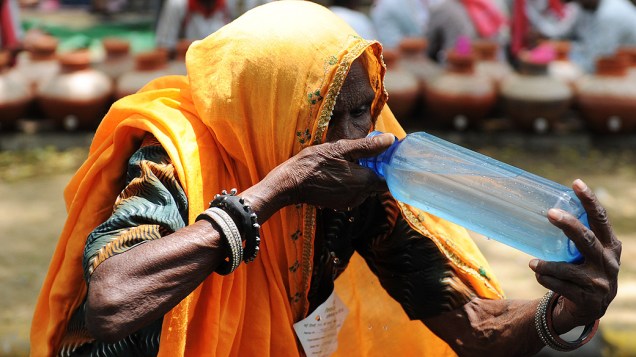 Mulher bebe água em um dia quente de verão em Nova Deli