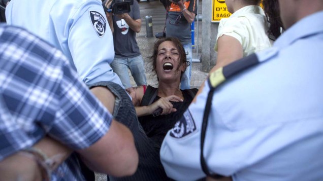 Policiais israelenses prendem uma ativista no aeroporto internacional David Ben Gurion, perto de Tel Aviv. Manifestantes se reuniram para receber ativistas que visitariam a Cisjordânia e outros territórios palestinos