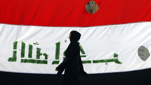 Iraquiana passa em frente a bandeira nacional durante comemorações da retirada das tropas americanas do Iraque
