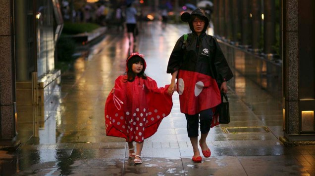 Mulher caminha com sua filha em dia chuvoso na cidade de Taipei, Taiwan