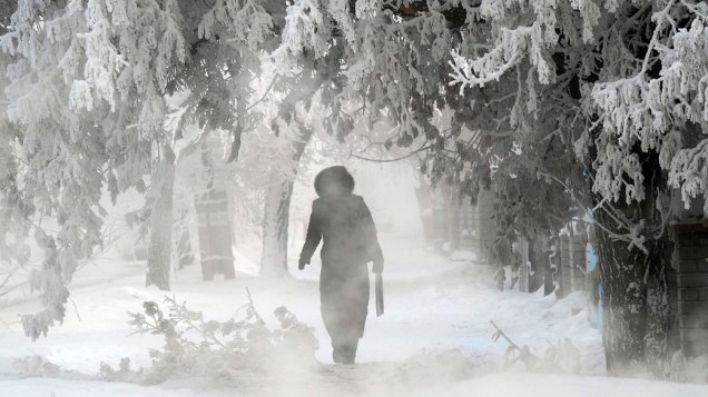 Mulher caminha por estrada coberta de neve na cidade de Pavlodar, Cazaquistão
