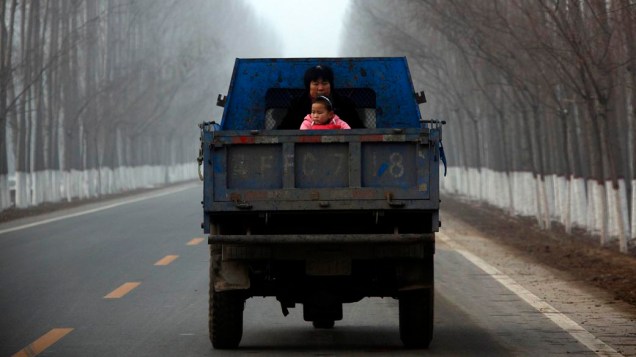 Mulher e filha andam na traseira de caminhão em estrada de Baoding, China
